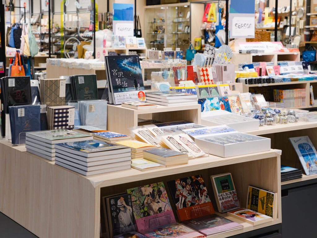 宮沢賢治をはじめとした、東北の作家をテーマにしたアイテムと書籍の棚の写真。